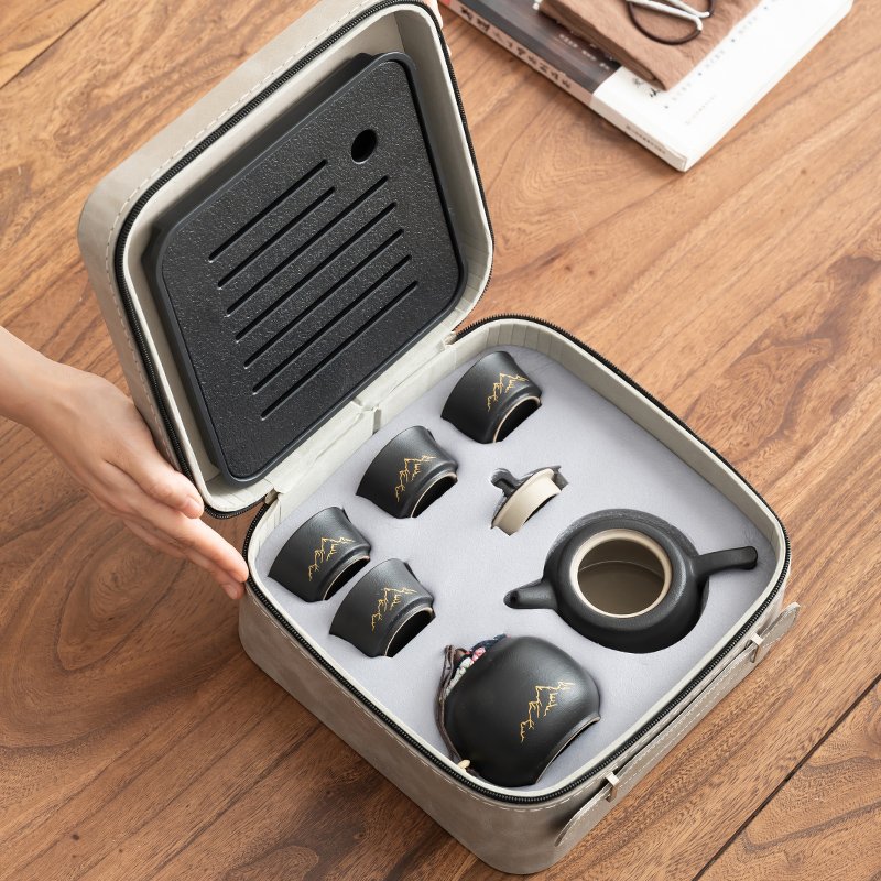 Open cream carrying case with fitted spaces for the teapot, four cups and tea jar, and the square tray inside the lid