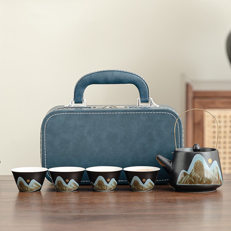 Complete four-cup mountain-landscape ceramic tea set with overhead-handle teapot and blue carrying case