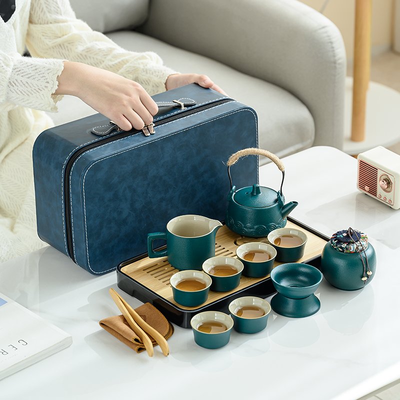 Woman carrying blue case beside teal ceramic travel tea set