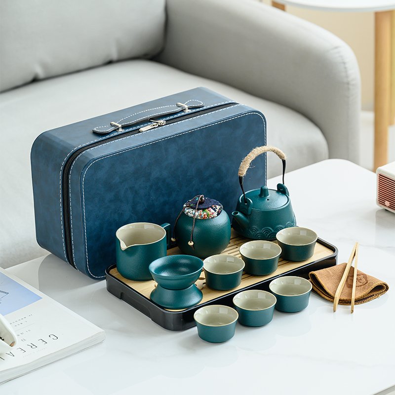 Teal ceramic travel tea set arranged with blue carrying case