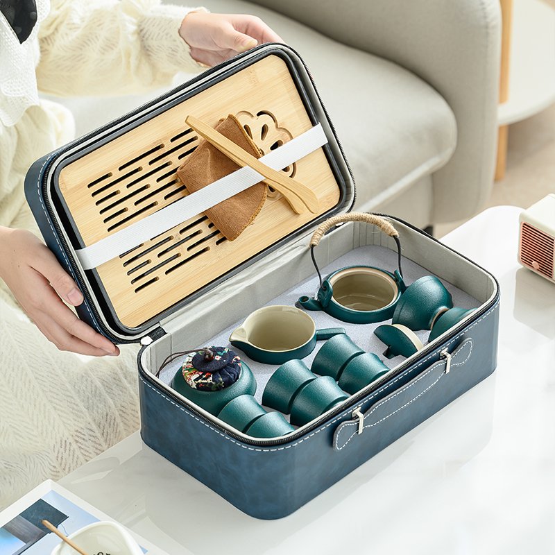 Open blue carrying case with tea vessels in divided compartments and bamboo tray inside the lid