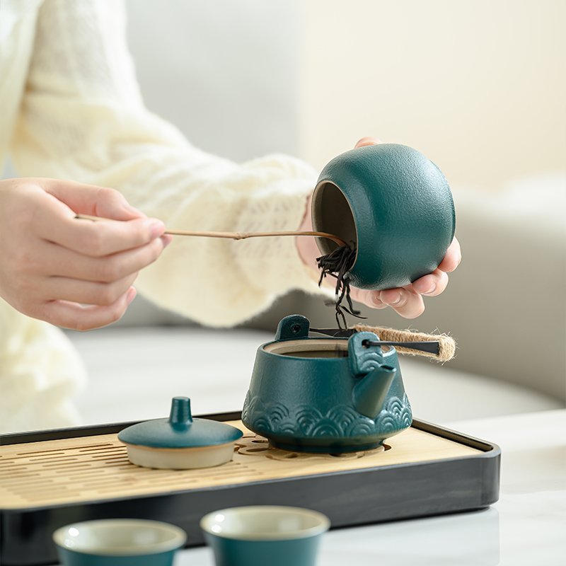Tea leaves being placed into teal ceramic teapot