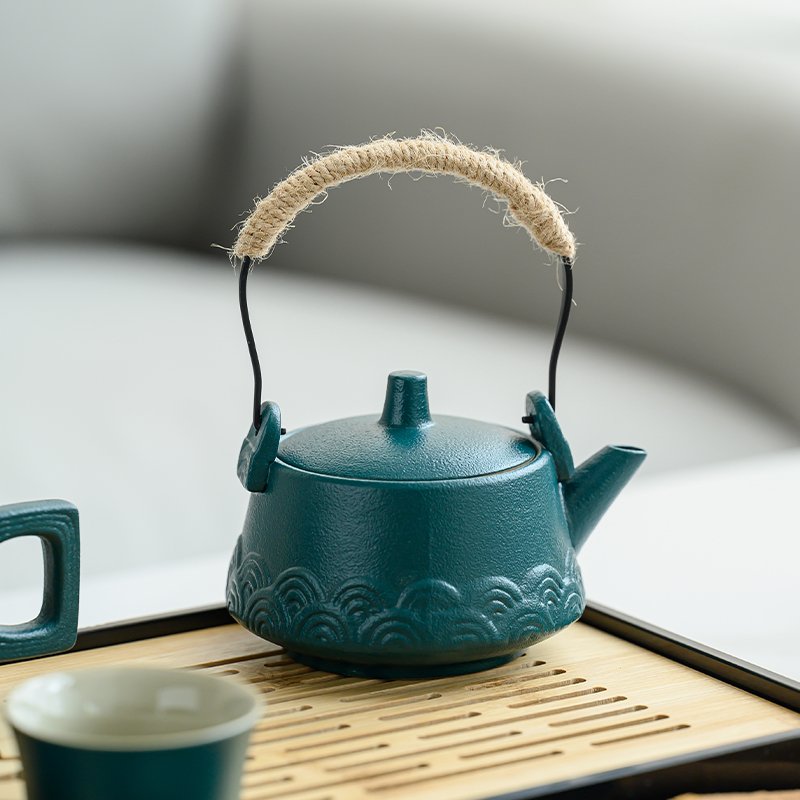 Close-up of teal ceramic handled teapot on bamboo tray