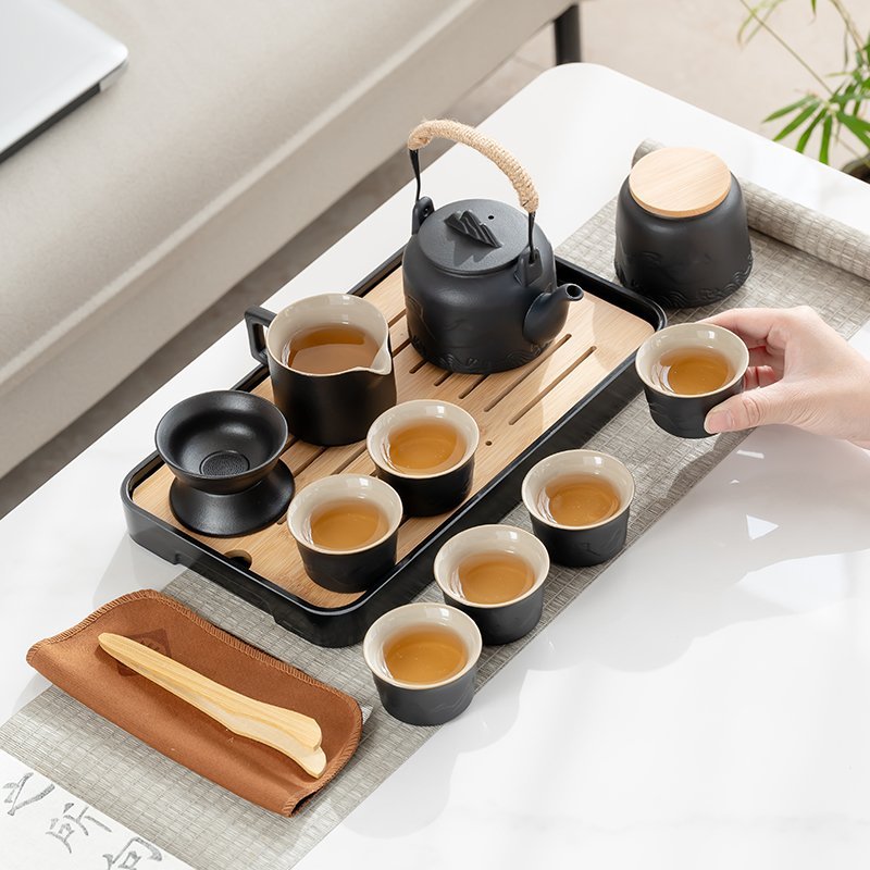One of six black tea cups held beside the mountain-and-wave relief teapot, jar and tea tray
