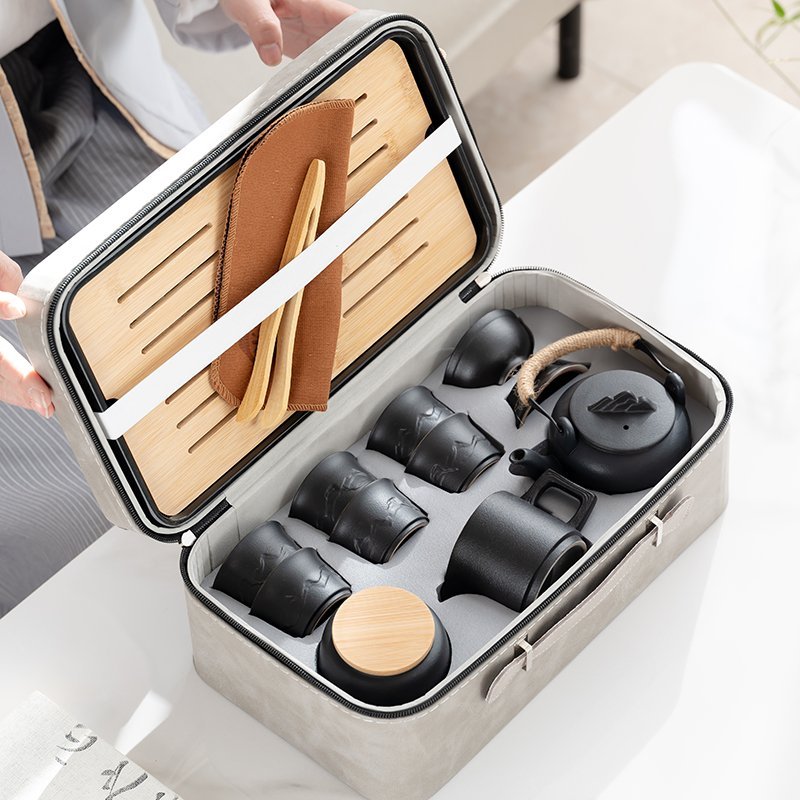Open gray carrying case with fitted spaces for the teapot, cups, pitcher, strainer and tea jar