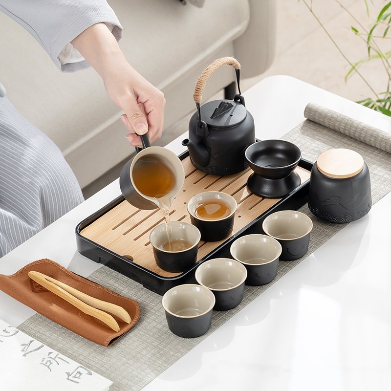 Fairness pitcher pouring tea into one of six matching cups beside the mountain-relief teapot