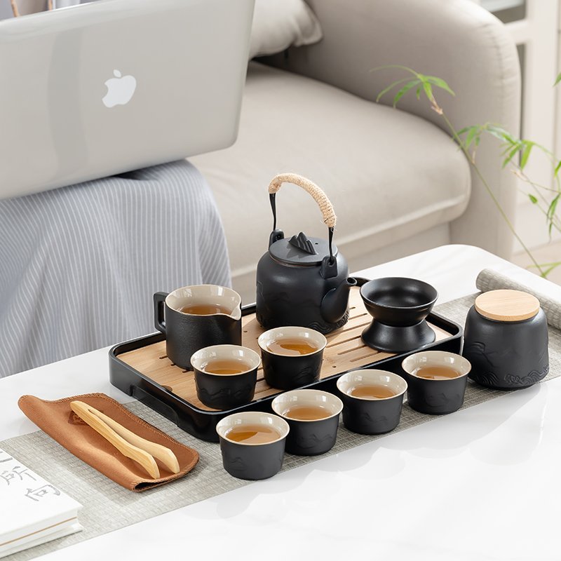 Six-cup black ceramic tea service arranged with a teapot, fairness pitcher, tea jar and slotted tray