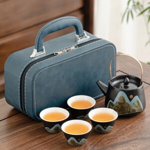 Blue carrying case beside a mountain-landscape ceramic teapot with overhead handle and four matching tea cups